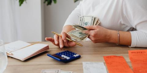 Person holding money, adding on a calculator