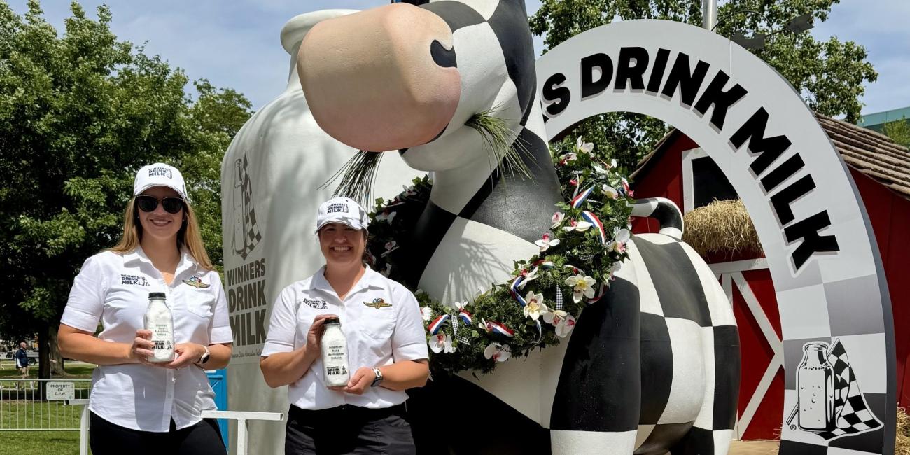 Abbie Herr with pint of milk in front of large cow