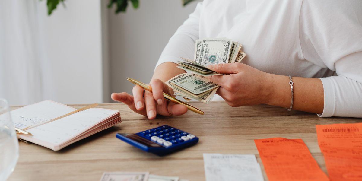 Person holding money, adding on a calculator